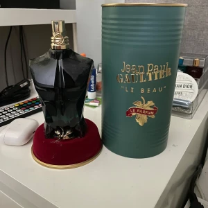 Jean Paul Gaultier Le Beau Le Parfum - Säljer en Jean Paul Gaultier Le Beau Le Parfum med en cool svart flaska formad som en manlig torso och gulddetaljer. Kommer med original grön cylinderförpackning med guldfärgad text och dekor. Perfekt för dig som gillar unika och lyxiga dofter. Den är 125ml och det kanske är 120ml kvar jag har knappt använt den