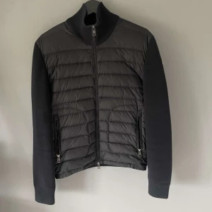 Marinblå moncler cardigan  - Marinblå Moncler cardigan med quiltad framsida i dun och stickade ärmar. Jackan har hög krage, tvåvägsdragkedja och två fickor med dragkedja. Klassisk Moncler-logga på ärmen. Perfekt för dig som vill ha en stilren och exklusiv look. Säljer den då min kille inte tycker den passar.                      Köpt på nk i göteborg, kan skicka bild på kvittot ifall man vill se. Diskuterbart pris vid snabbt köp, Skicket är 9/10. Öppen för byten!