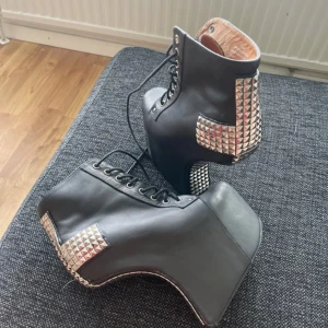 Jeffrey Campbell Holy - Använda 4-5 ggr, nypris 2200kr. Unika svarta boots från Jeffrey Campbell med extrem plattform och hög klack. Skorna har snörning framtill och är dekorerade med silverfärgade pyramidnitar på hälen och sidorna. Tillverkade i skinn med Havana Last. Perfekt för dig som vill sticka ut med edgy stil.