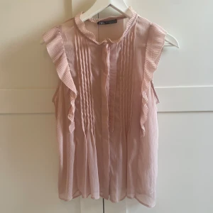 Rosa volangblus från Zara - Supersöt ljusrosa blus från Zara med volangdetaljer längs axlarna och kragen. Endast testad. Priset är prutbart. 