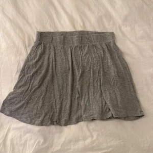 Grå kortkjol från Red & Blue - En enkel och mjuk grå kortkjol från Red & Blue. Kjolen har en bred resår i midjan och är tillverkad i bomullsmaterial som gör den skön att bära. Passformen är normal och kjolen har en lätt utställd form som ger en avslappnad vibe.