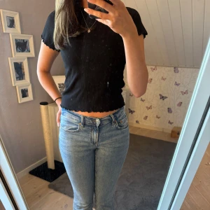 Svart croppad ribbad topp - Säljer en svart croppad t-shirt med korta ärmar och ribbad struktur. Toppen har vågiga kanter vid ärmslut och nederkant. En gammal favorit topp🩷🥹