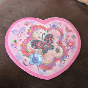 Färgglada armband i smyckeskrin - Säljer flera söta armband med pärlor i lila, rosa, grönt och silver. Armbanden ligger i ett hjärtformat smyckeskrin med spegel och dansande ballerina. Skrinet är rosa med fjärilar och blommor i glittriga färger, perfekt för att förvara dina favoritsmycken.