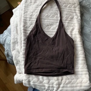Brun halterneck linnetopp från Divided - Säljer en brun halterneck linnetopp från Divided. Toppen har djup v-ringning och är ärmlös med smala band som knyts i nacken. Perfekt till sommaren och enkel att matcha med jeans eller kjol.