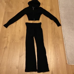 Svart set - Säljer ett par svarta stickade byxor tillsammans med tröja. Byxor med bred, ribbad och hög midja. Byxorna har en rak och lite utsvängd passform, perfekta för en chill och trendig look. Mjukt material som känns skönt mot huden. Tröja med dragkedja. Säljs som ett set. Priset är för båda plaggen tillsammans. Hämtas i Eskilstuna, Borsökna. 