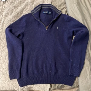 Ralph lauren half zip  - Snygg marinblå stickad tröja från Polo Ralph Lauren med halv dragkedja och ribbad krage. Tröjan har långärmade ärmar och en liten broderad logga på bröstet. Perfekt för dig som gillar klassisk stil med en modern touch Det är stl S men är ganska så liten så passar dig som är runt 170-178 och ganska smal! 