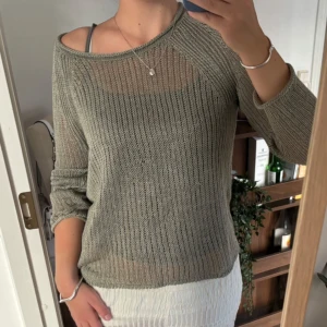 Grå/ grön ribbstickad tröja med lång ärm - Säljer en grå ribbstickad tröja med lång ärm och rund halsringning. Tröjan har en avslappnad passform och är perfekt för lager-på-lager. Enkel och stilren design som funkar till många olika outfits.