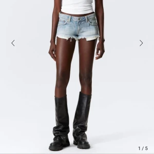 Ljusblå jeansshorts med fransar - Säljer ett par ljusblå jeansshorts med rå kant och fransar. De har klassisk femficksdesign, låg midja och slitna detaljer för en cool vibe. Perfekta för varma dagar och festivalhäng.