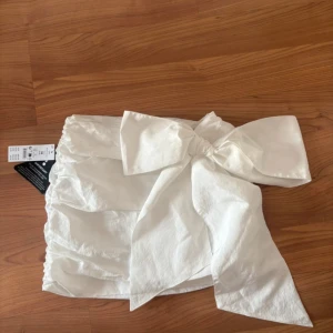 Vit kjol med stor rosett från Gina Tricot - Sjukt snygg kjol från Gina Tricot🤩Stor rosett på sidan, har även en liten dragkedja på samma sida som rosetten som ej syns.❤️Alldrig använd, säljer pågrund av att den var för liten🙁