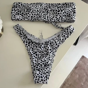 Vit och svart prickig bandeau bikini - Säljer en snygg bandeau bikini från shein, aldrig använd men skyddet är bortdraget. 
