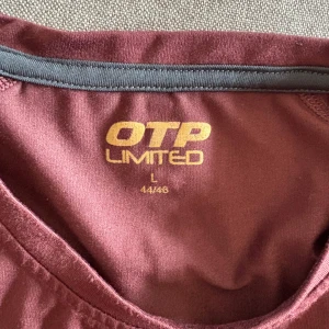 Vinröda LIMITED träningstights - Snygga vinröda träningstights från LIMITED med guldiga detaljer och dragkedja vid benslutet. Tightsen har en liten ficka med dragkedja bak i midjan och är tillverkade i ett stretchigt syntetmaterial som sitter tight och bekvämt.