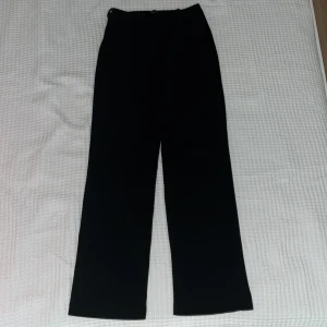 Svarta kostymbyxor från Vero Moda XS - Svarta kostymbyxor från Vero Moda i storlek XS. Byxorna har rak passform och klassisk midja, perfekta för en clean och stilren look. Materialet känns mjukt och följsamt, vilket gör dem bekväma att bära hela dagen.