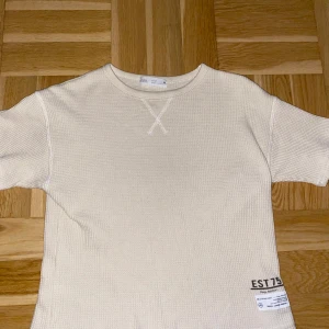 Beige kortärmad tröja från Zara - Beige tröja med märke nere på höger kant Tröjan har en strukturerad, ribbad yta.nästan alldrig använd 