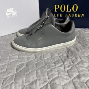 Axel arigato skor - Säljer ett par schyssta Axel arigato skor som är i bra skick förutom en liten skada på bakre delen av höger sko, visar bild vid intresse. Sko påse medföljer. Hör av er vid frågor, eller funderingar. BVSA!