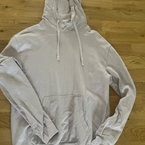 Ljuslila hoodie från Cubus XS - En stilren ljuslila hoodie från Cubus i storlek XS. Tröjan har huva med snörning, magficka och långa ärmar med ribbade muddar. Tillverkad i mjuk bomullsmix som känns skön mot huden. Perfekt för chill dagar eller när du vill ha en enkel och clean look. En liten fläck som man ser på bilden