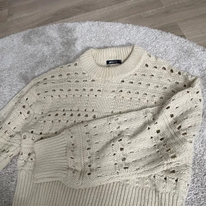 Beige stickad tröja från Gina Tricot - Säljer en beige stickad tröja från Gina Tricot i storlek XS. Tröjan har ett snyggt hålmönster över hela och breda ribbade muddar vid hals, ärmslut och nederkant. Perfekt för dig som gillar en chill och trendig look med lite struktur.