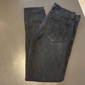 Replay Anbass svarta jeans, stl 30/30 - Säljer ett par svarta Replay Anbass jeans i storlek 30/30. Jeansen har klassisk femficksdesign, svarta sömmar och Replay-logga på fickan. Modellen är slim och tillverkad i stretchig bomullsdenim för skön passform.
