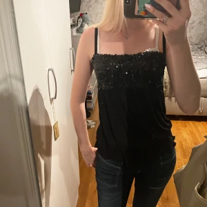 Fest topp med volangkant  - Säljer en fest topp, som har paljetter upptill och volang som kant, band som går att ändra längd på.  Skick är bra. Storlek skulle jag säga är S-L då den är stretchig, står L på etiketten ,men dock har jag xs-s och den passar mig. Pris 169kr. Skriv vid funderingar!💕