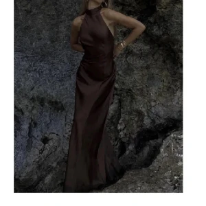 Brun långklänning i satin med öppen rygg - Supersnygg brun långklänning i glansigt satinmaterial. Klänningen har hög hals, är ärmlös och har en öppen rygg med knytband. sparsamt använd! Perfekt till bal💓 storlek 32 men passar 34! Pris kan diskuteras