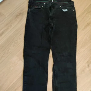 Svarta raka jeans - Svarta jeans med klassisk femficksdesign och raka ben. Jeansen har en enkel look utan synliga slitningar eller dekorationer, perfekt för en clean och stilren outfit. Passar dig som gillar en tidlös vibe.