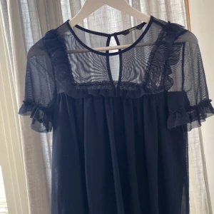 Marinblå meshtröja från ONLY XS - Säljer en marinblå tröja från ONLY i storlek XS. Tröjan har transparent mesh upptill, volangdetaljer vid axlar och ärmar samt en knapp i nacken. Du står för frakten, vid mer info skriv
