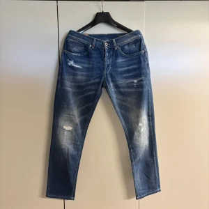 Dondup George  - Säljer ett par blå jeans från Dondup med snygga slitningar och ljusa tvättade partier. Snygga jeans i mycket bra skick. Det är storlek 34 men kommer passa perfekt för dig som har 32-33! Tveka inte att höra av dig om du har fler frågor!