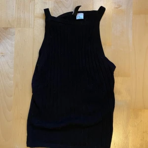 Svart ribbad linnetopp från H&M Divided - Säljer en svart ribbad linnetopp från H&M Divided i storlek XS. Toppen är ärmlös med breda axelband och har en tight passform. Perfekt att styla med jeans eller kjol för en clean look.
