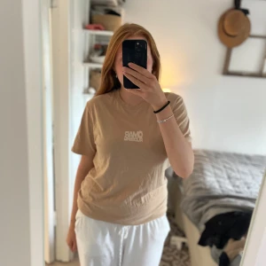 Beige Omar Rudberg t-shirt - Säljer en beige t-shirt med tryck från Omar Rudberg, säljer pga att jag inte känner mig bekväm i färgen och har annan merch. Framsidan har ett vitt logotryck och baksidan har ett stort motiv med Omar Rudberg och text. T-shirten har rund hals och korta ärmar, tillverkad i mjukt material, den går inte längre att köpa och är i jätte bra skick, bara använd ett fåtal gånger🫶🏼Pris kan diskuteras