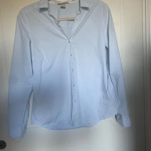 Figursydd skjorta - Blåvit randig figursydd skjorta ifrån Hm. Storlek 38. Finns ett litet blått streck på framsidan men kanske kan gå bort i tvätten. Använd 1 gång så annars mycket fint skick! 💞