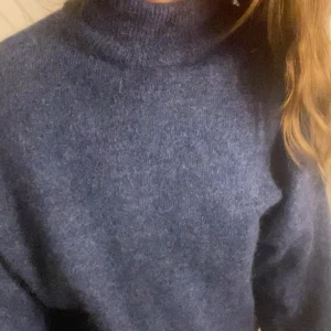 Blå stickad polotröja från Object - Mysig blå polotröja från Object i storlek S. Tröjan är stickad med en hög krage och har långärmade ärmar. Perfekt för dig som gillar en enkel och chill look med lite loose passform. Färgen är mörkblå och materialet känns mjukt och fluffigt.