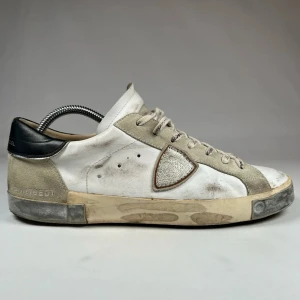 Vita och grå sneakers från Philippe Model - Snygga vita och grå sneakers från Philippe Model med en unik design. Skorna har snörning och en rund tå, med en kontrasterande svart häl. Perfekta för en avslappnad stil. 100% ektighetsvarifierade av proffs💯 snygga nypris 3699 vårt pris 1799