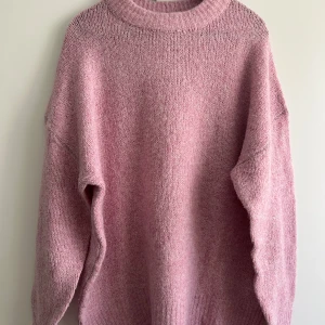 Rosa stickad tröja - Mysig rosa stickad tröja med rund hals och långa ärmar. Perfekt för kyliga dagar när du vill hålla dig varm och bekväm. Tröjan har en enkel och stilren design som passar till många olika outfits.