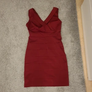 Vinröd klänning med v-ringning - Snygg vinröd klänning med v-ringad hals och figurnära passform. Perfekt för en kväll ute eller en speciell tillställning. Klänningen har en elegant design med breda axelband och dragkedja. Köparen står för frakten✨️