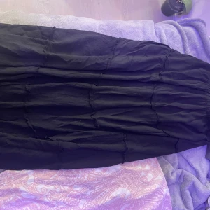 Svart långkjol  - Snygg svart långkjol med knyt detaljer. Perfekt för en stilren look. Kjolen har en elegant och enkel design som passar till många olika tillfällen.