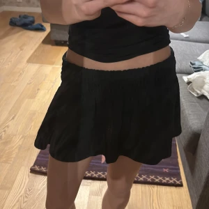 Svart kortkjol - Snygg svart kortkjol med en lös passform. Perfekt för en stilren look. Kjolen har en enkel design utan mönster eller detaljer, vilket gör den lätt att matcha med olika toppar.