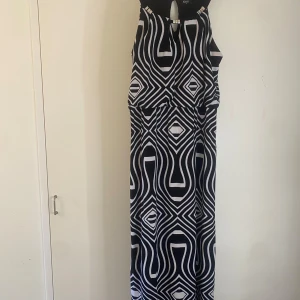 Svartvit mönstrad klänning från Klass - Snygg långklänning från Klass i svartvitt geometriskt mönster. Klänningen är ärmlös med en elegant öppning vid halsen och har en rak passform. Perfekt för en stilfull look! Den är öppen nere vid benen på båda sidorna ungefär upp till knät men trådarna är lite slitna nere vid öppningen men det är inget som märks när man har på sig den! Priset går alltid att diskutera:) 