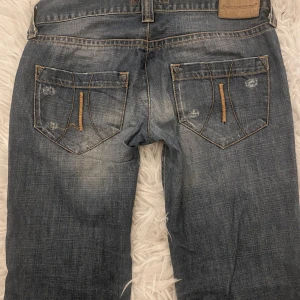Low waist bootcut jeans - Säljer ett par blå jeans med snygga slitningar. Dom är låg midjade och bootcut! Står ej någon storlek man skulle gissa mellan 36 och 38💕