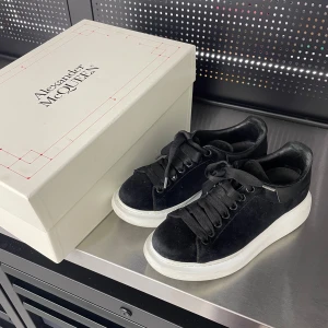 Svarta sneakers från Alexander McQueen - Snygga svarta sneakers från Alexander McQueen med en chunky vit sula. Skorna har snörning och är tillverkade i valvet material vilket ger en lyxig känsla. Perfekta för att ge din outfit en stilren touch. Skick enligt bilder, skolåda medföljer
