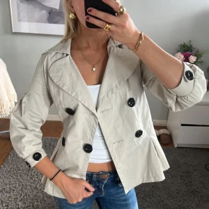 Trekvartsärmad kappa - Beige/grå Trekvartsärmad kappa/trenchcoat från attenif, köpt i Paris! Otroligt efterfrågad, snygg och perfekt nu till hösten! Köp gärna via ”köp nu”. Lite trasig inuti vid armarna, men ingen som syns ut. Även två små fläckar men kan nog tvättas bort!