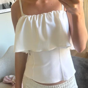 Vit axelbandslös topp - Jätte söt topp med volangdetalj. Använd fåtal gånger. Är osäker på om den fortfarande säljs hos Zara
