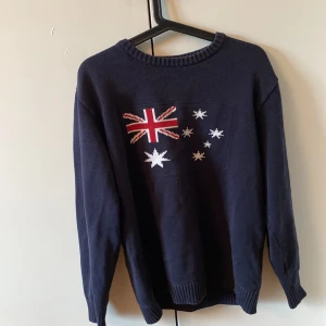 Mörkblå stickad tröja från Holebrook Sweden - Säljer en mörkblå stickad tröja från Holebrook Sweden med Australiens flagga och stjärnor på framsidan. Tröjan har långa ärmar och ribbstickade muddar vid ärmslut och nederkant. Perfekt för kyliga dagar!