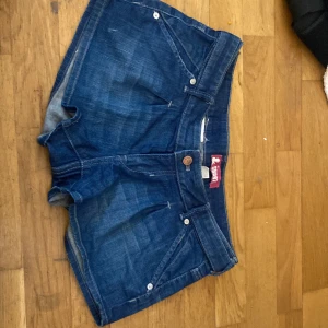 Blå jeansshorts  - Snygga blå jeansshorts från & med klassisk femficksdesign och knappdetaljer. Perfekta för en avslappnad stil. De har en normal passform och är tillverkade i slitstarkt denim.