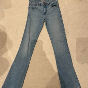Blå bootcut jeans från Wrangler - Ljusblåa Wrangler jeans. Normal midja, midwaisted. Inte använda. Midjemåttet: 33cm. Innerbenslängd: 80cm. W26 L32 Pris kan diskuteras!