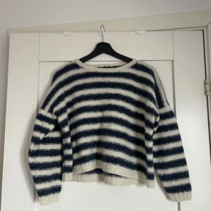 Randig stickad tröja - Säljer en mysig randig stickad tröja i blått och vitt. Tröjan har en croppad passform och långa ärmar, perfekt för kyligare dagar. Den är handsydd från Danmark 