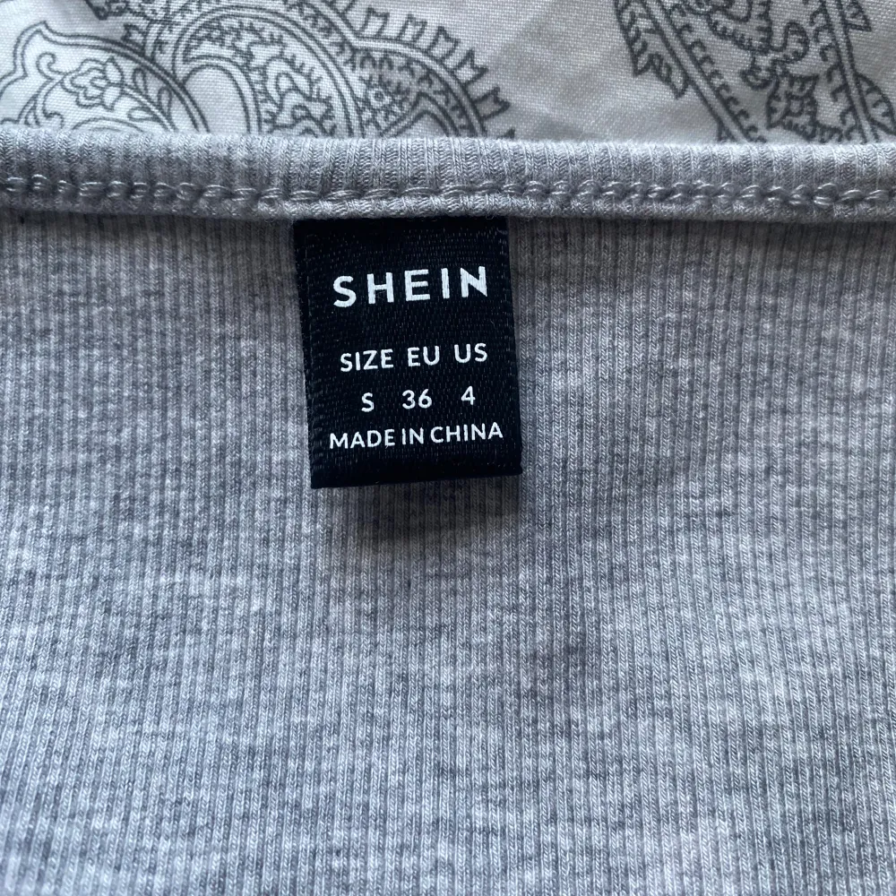 Säljer en grå ribbad t-shirt från Shein. T-shirten har en rundad hals och korta ärmar, inga defekter och använd ett fåtal gånger. Väldigt bekväm. T-paidat.