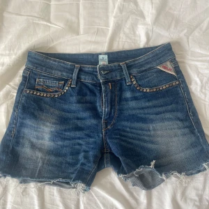 Blå jeansshorts från Replay - Så finaaaa blå jeansshorts från Replay med fransiga kanter och nitar längs fickorna. Perfekta för en avslappnad sommarlook. Klassisk femficksdesign med knapp och dragkedja framtill. Perfect för sommar!!!💘