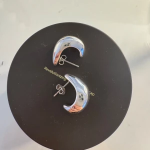 Örhängen otherstories - Snygga och moderna silverfärgade örhängen i form av halvmånar. Perfekta för att ge en stilren touch till din outfit. De har en slät och blank yta som reflekterar ljuset fint.