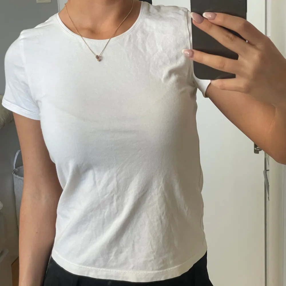 Säljer en klassisk vit t-shirt med korta ärmar. Perfekt basplagg för alla tillfällen. Tillverkad i mjukt material för en bekväm passform.. T-paidat.