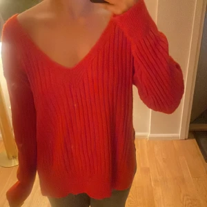 Neon ribbad tröja - Säljer en snygg röd ribbad tröja med v-ringning. Tröjan har långa ärmar och en avslappnad passform. Den är både stilren och bekväm, vilket gör den till ett mångsidigt tillskott i garderoben.