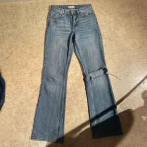 Low waist bootcut - Säljer ett par blå jeans från Ginatricot med en avslappnad bootcut-stil. De har en sliten look med en reva på ena benet. Perfekta för en casual stil. Likadana som saga stq  har en fläck men tvättas bort enkelt använda 5 gånger och kan ej ha dem längre ❤️ diskuterbart pris
